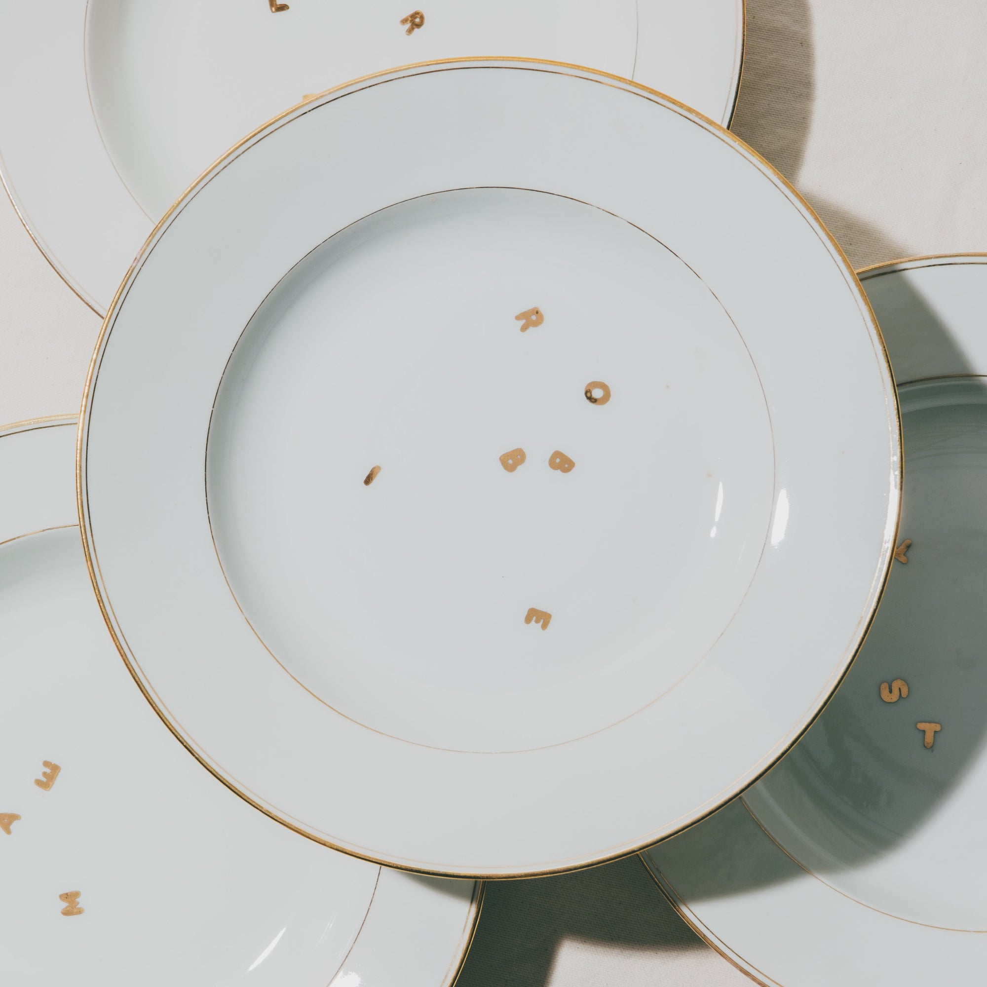 Cette photo représente une assiette qui a été décorée au décalcomanie avec les lettres en or du prénom Robbie lors d'un atelier de décor au décalcomanie