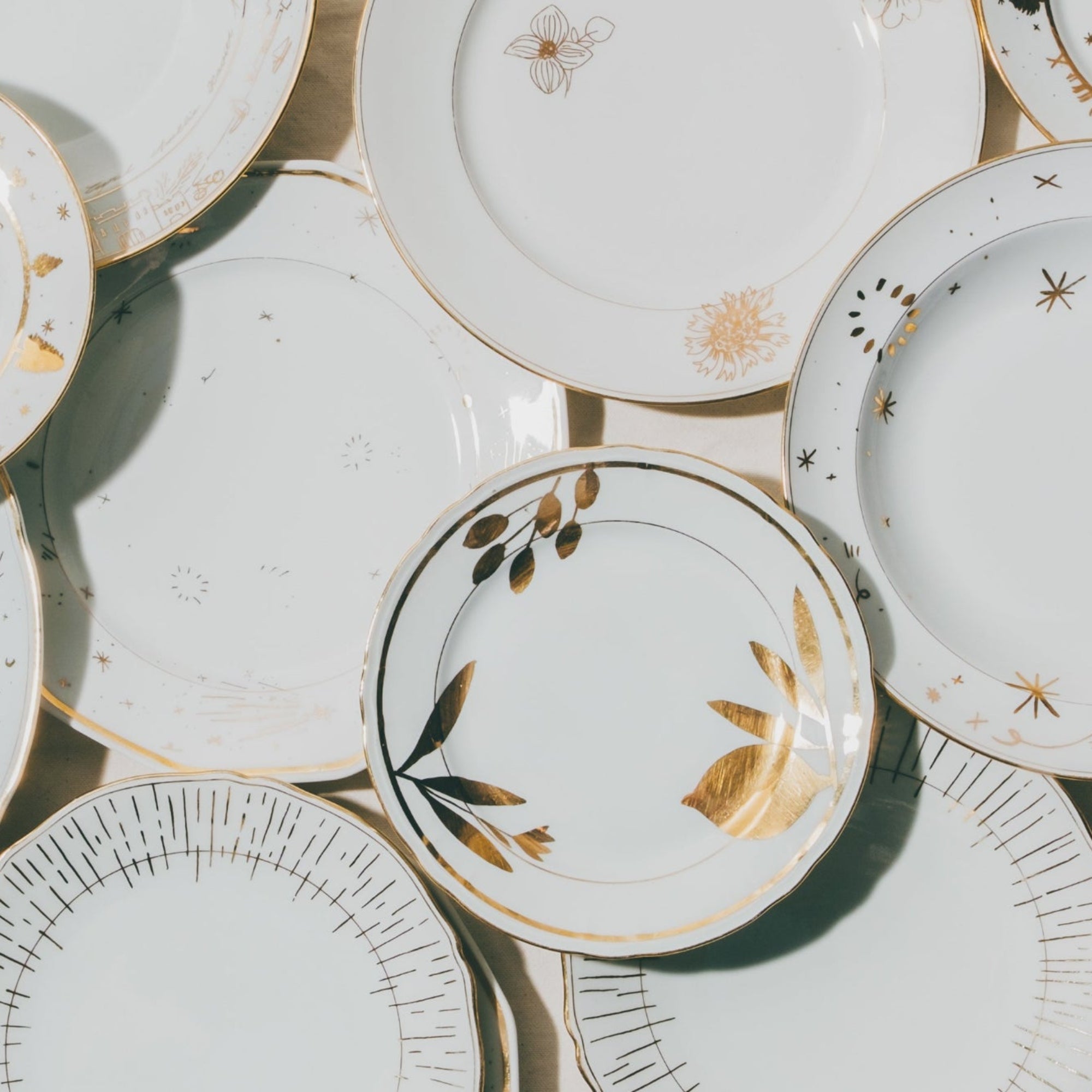 Cette photo représente un ensemble d'assiettes qui ont été décorées à l'or et à la plume lors d'un atelier de 3h à l'Atelier Grand Soleil à Paris