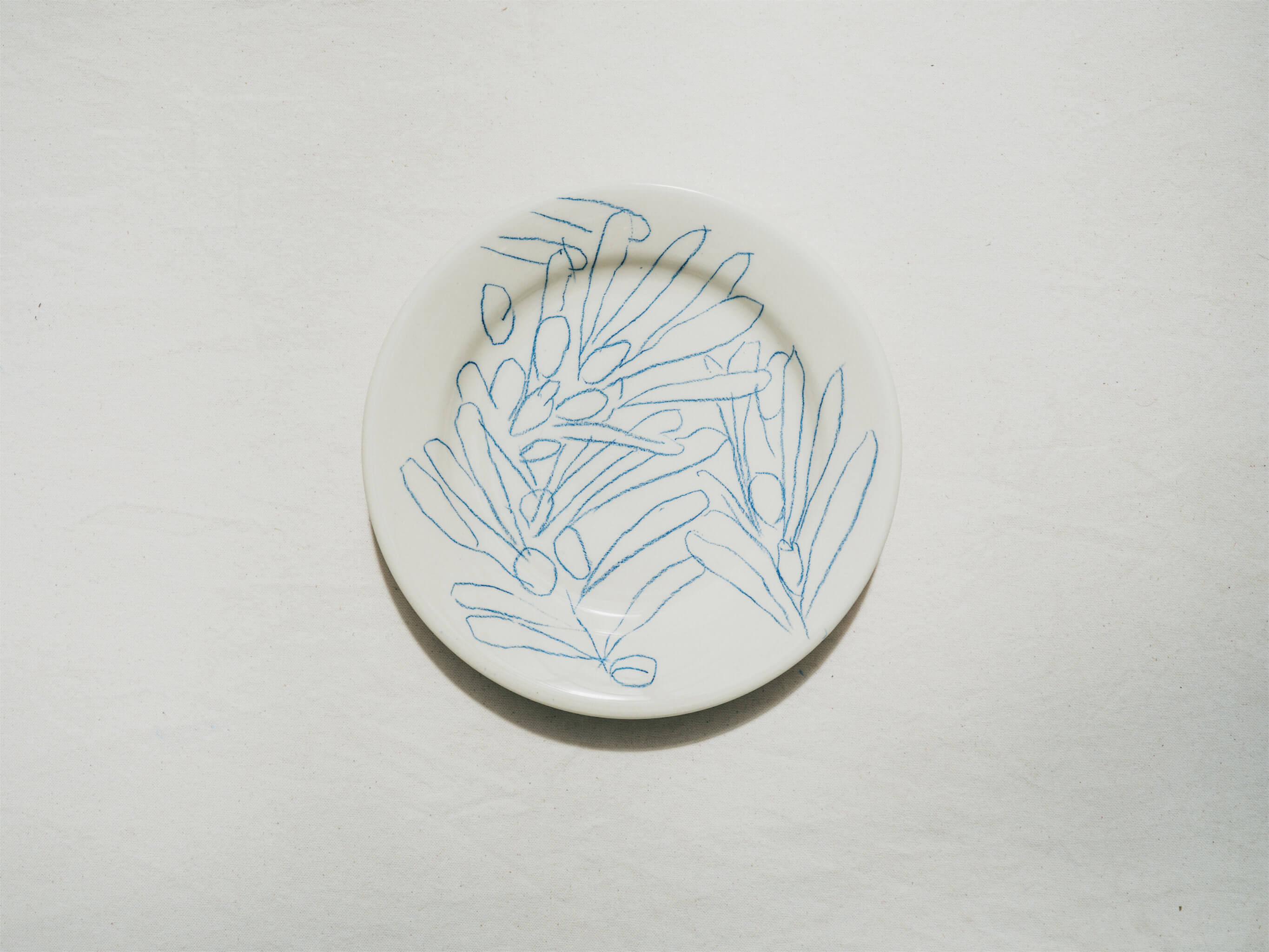 Assiette en faience décorée au crayon à oxydes puis émaillée par l'atelier grand soleil, à Paris. Personnalisable avec une phrase. Motif : olives