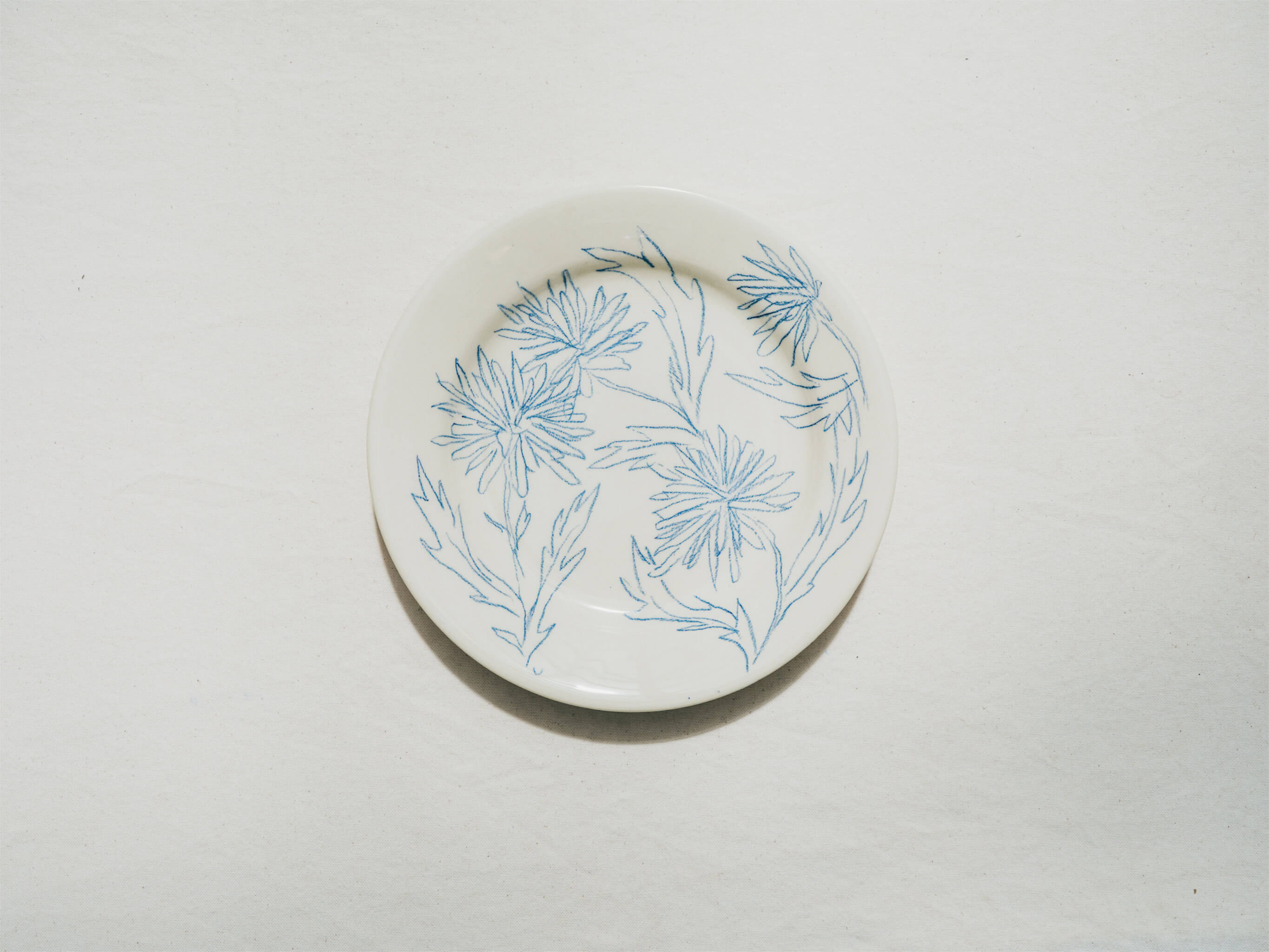 Assiette en faience décorée au crayon à oxydes puis émaillée par l'atelier grand soleil, à Paris. Personnalisable avec une phrase. Motif : pissenlit