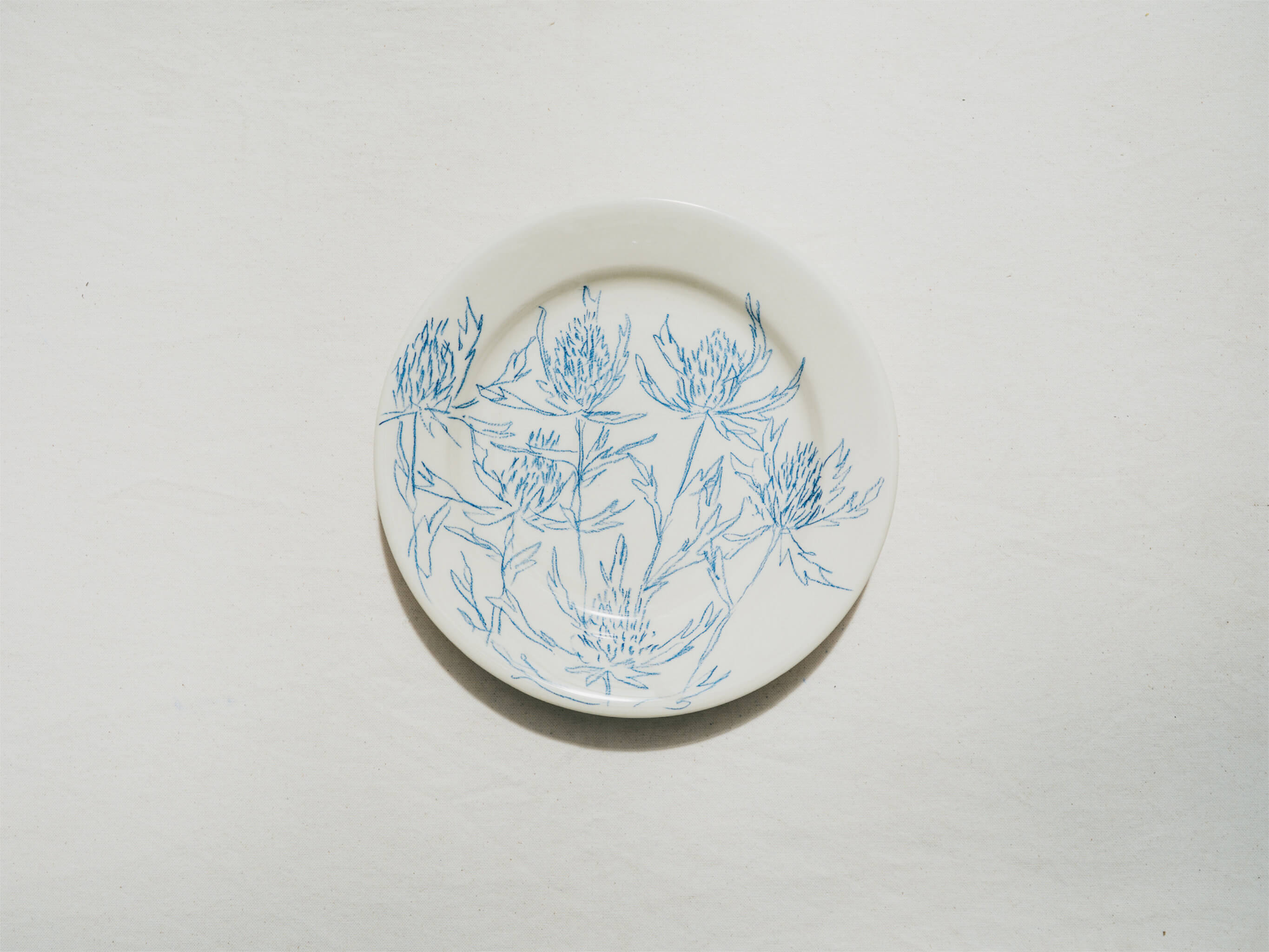 Assiette en faience décorée au crayon à oxydes puis émaillée par l'atelier grand soleil, à Paris. Personnalisable avec une phrase. Motif : chardons