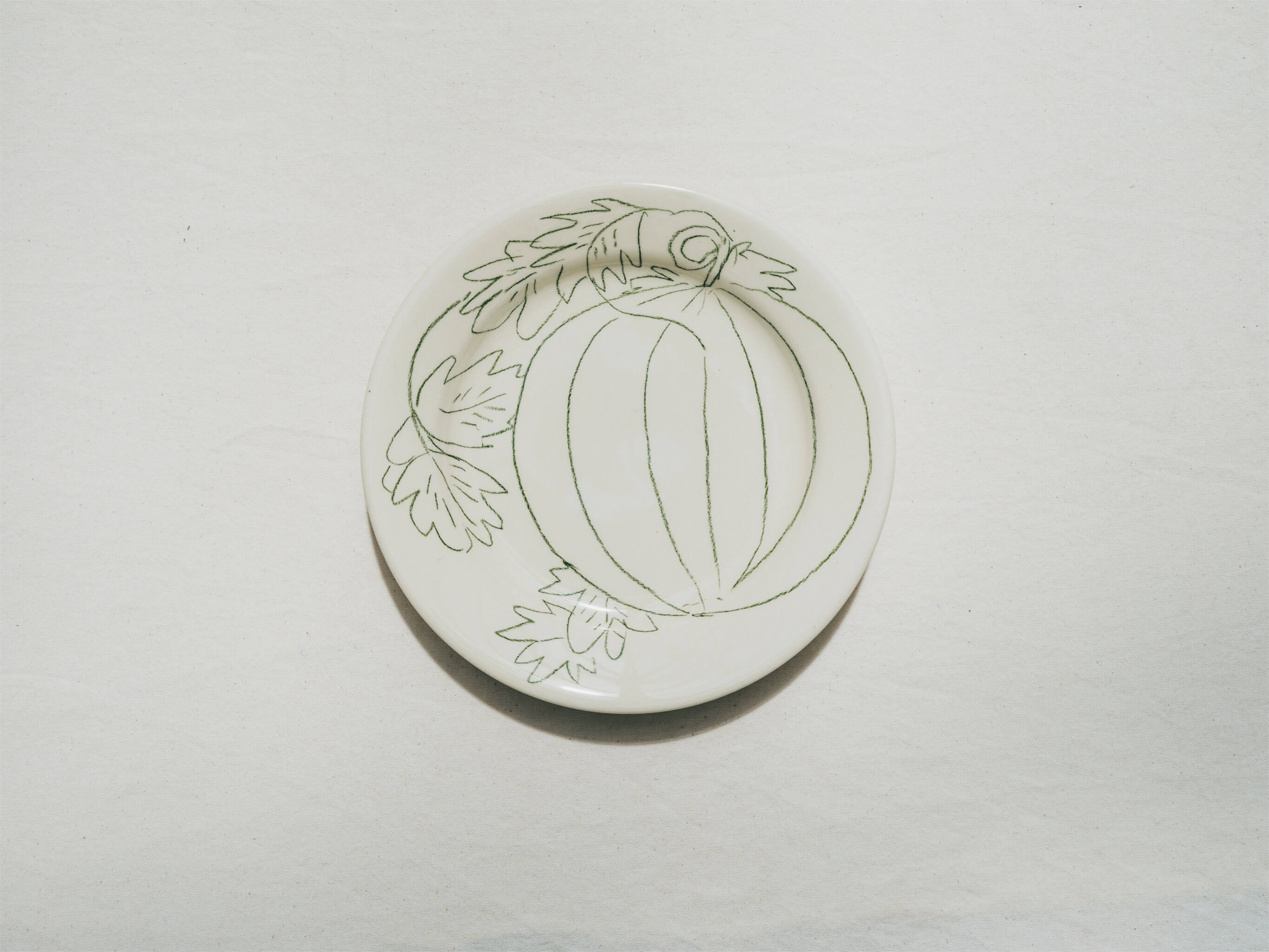 Assiette en faience décorée au crayon à oxydes puis émaillée par l'atelier grand soleil, à Paris. Personnalisable avec une phrase. Motif : melon