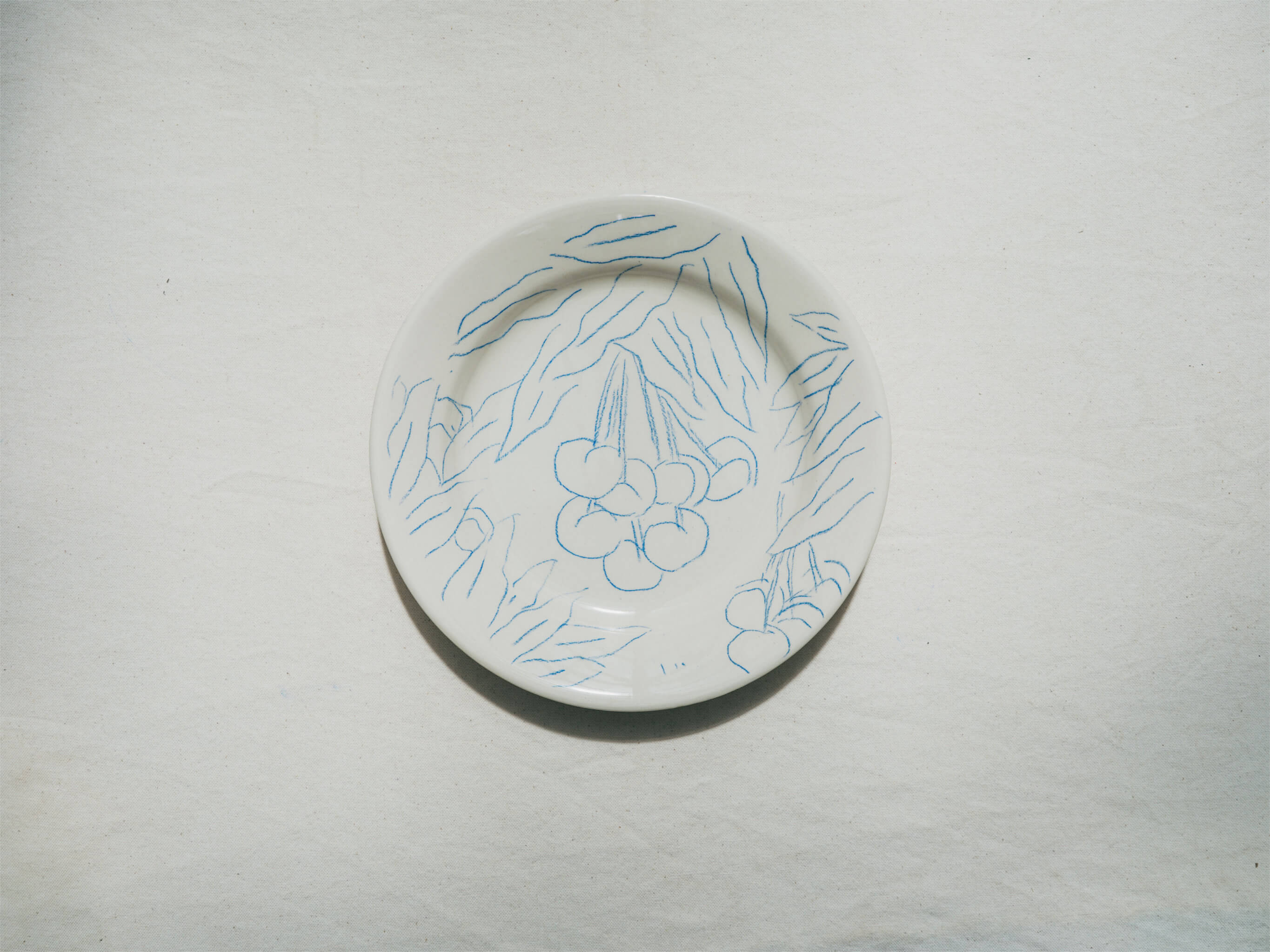 Assiette en faience décorée au crayon à oxydes puis émaillée par l'atelier grand soleil, à Paris. Personnalisable avec une phrase. Motif : cerises