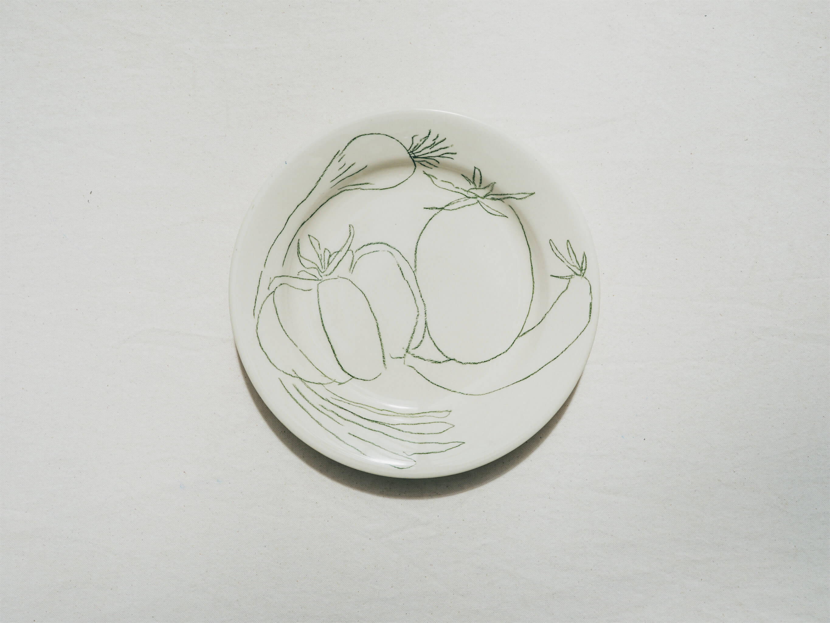 Assiette en faience décorée au crayon à oxydes puis émaillée par l'atelier grand soleil, à Paris. Personnalisable avec une phrase. Motif : tomate et oignons frais