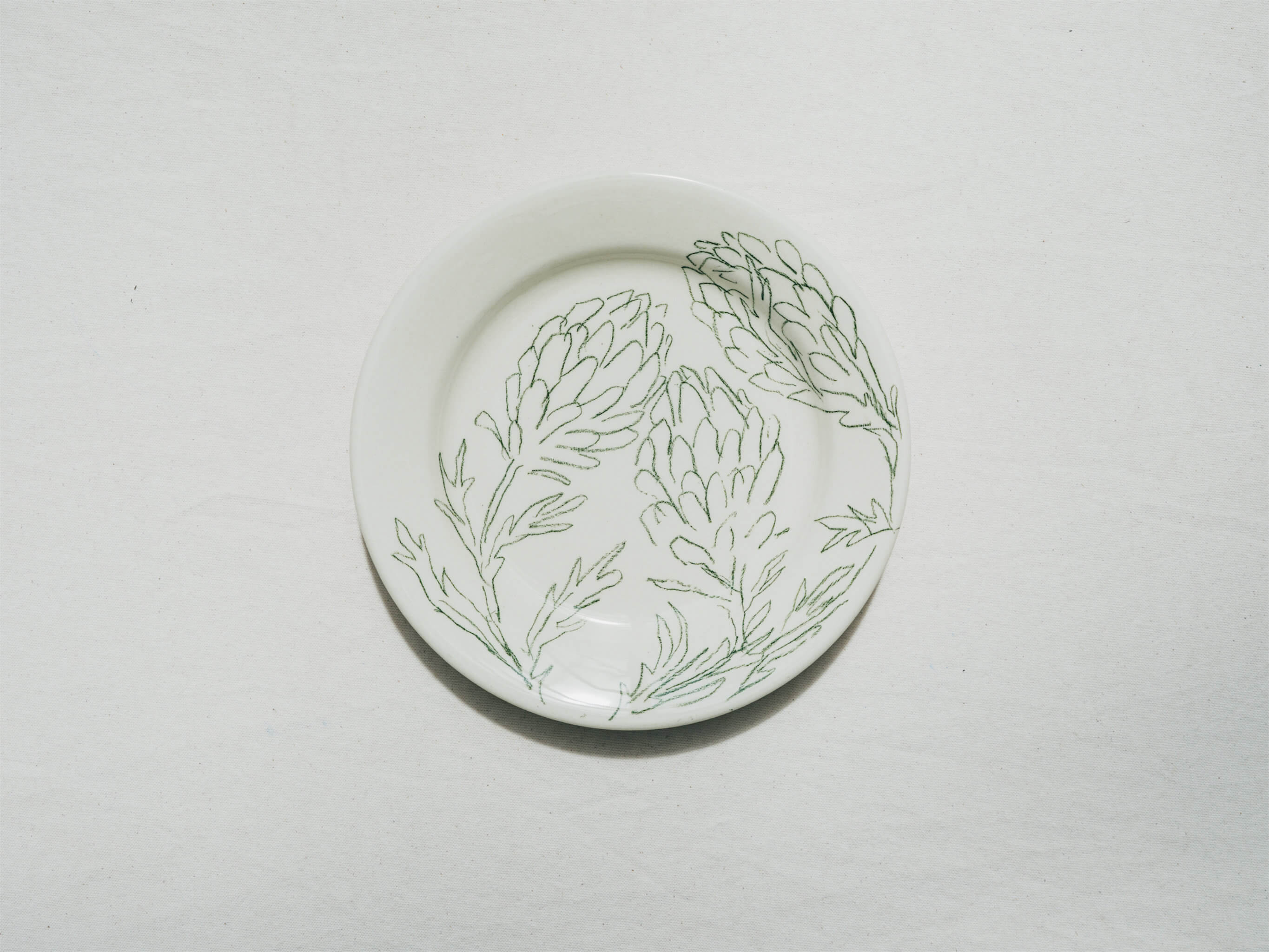 Assiette en faience décorée au crayon à oxydes puis émaillée par l'atelier grand soleil, à Paris. Personnalisable avec une phrase. Motif : artichauts