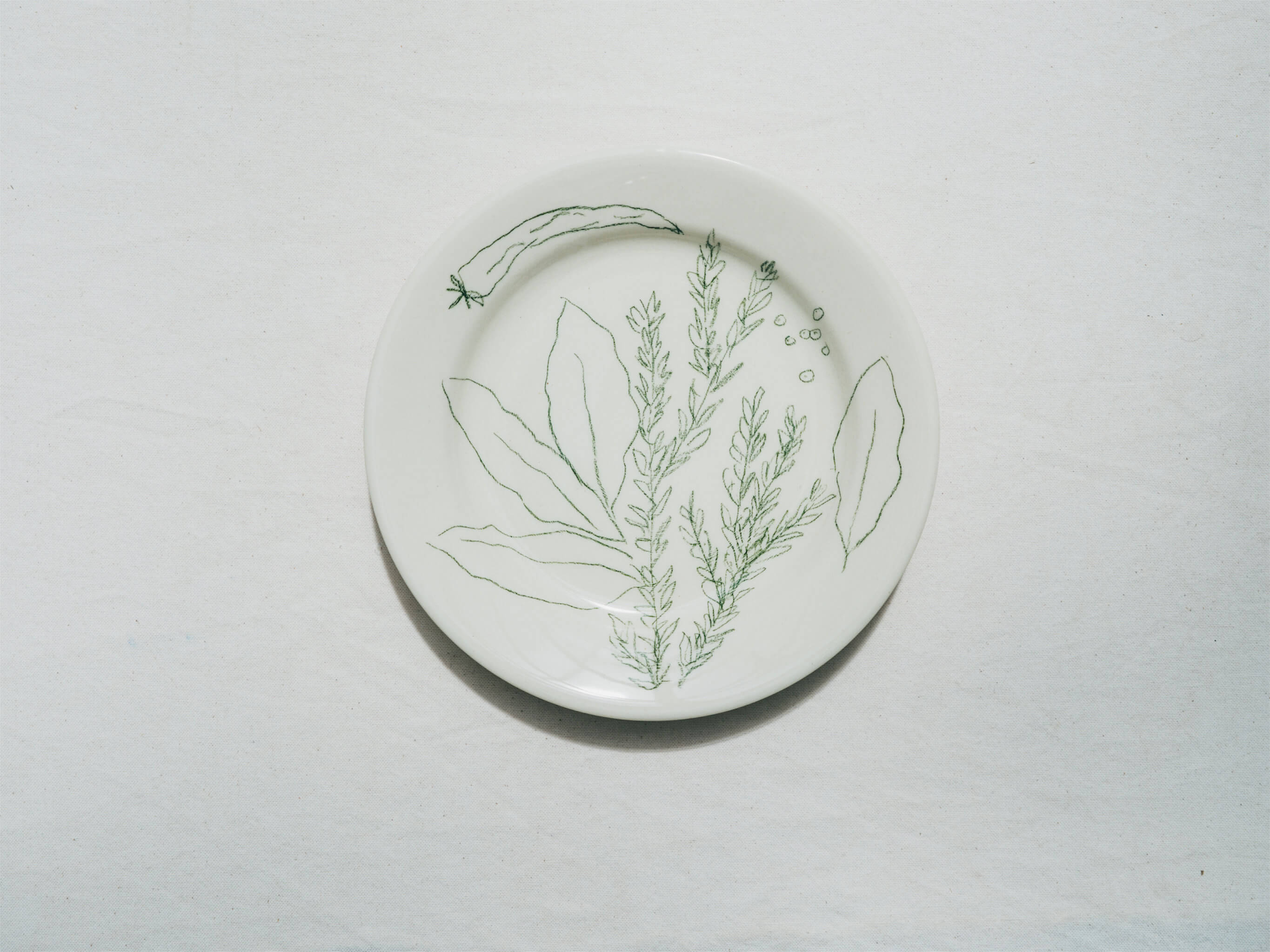 Assiette en faience décorée au crayon à oxydes puis émaillée par l'atelier grand soleil, à Paris. Personnalisable avec une phrase. Motif : laurier et romarin