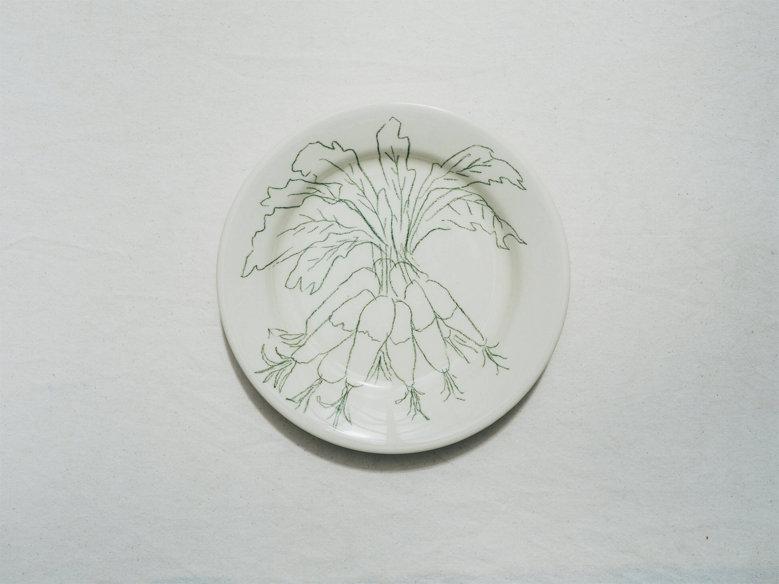 Assiette en faience décorée au crayon à oxydes puis émaillée par l'atelier grand soleil, à Paris. Personnalisable avec une phrase. Motif : radis