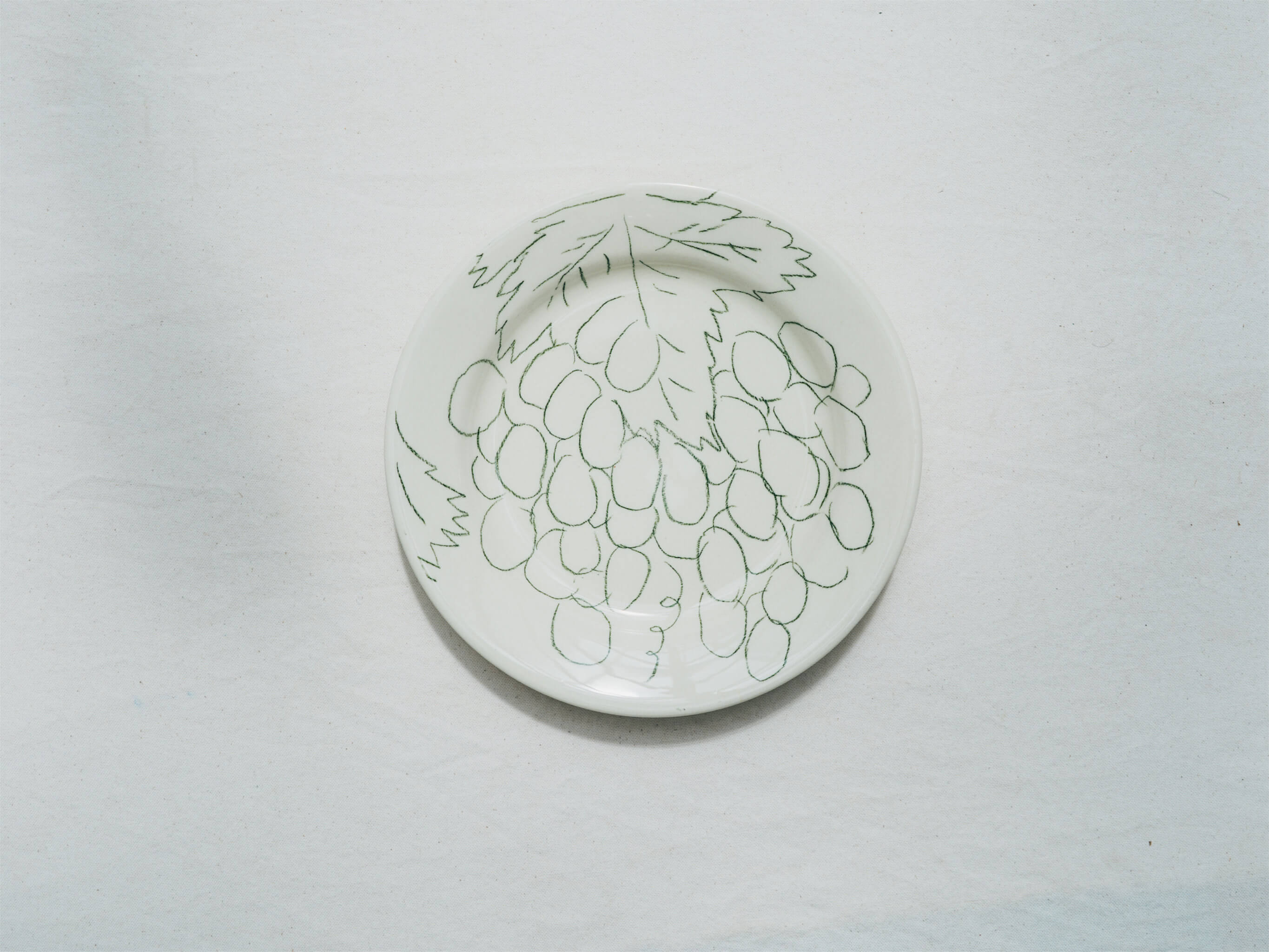 Assiette en faience décorée au crayon à oxydes puis émaillée par l'atelier grand soleil, à Paris. Personnalisable avec une phrase. Motif : raisin