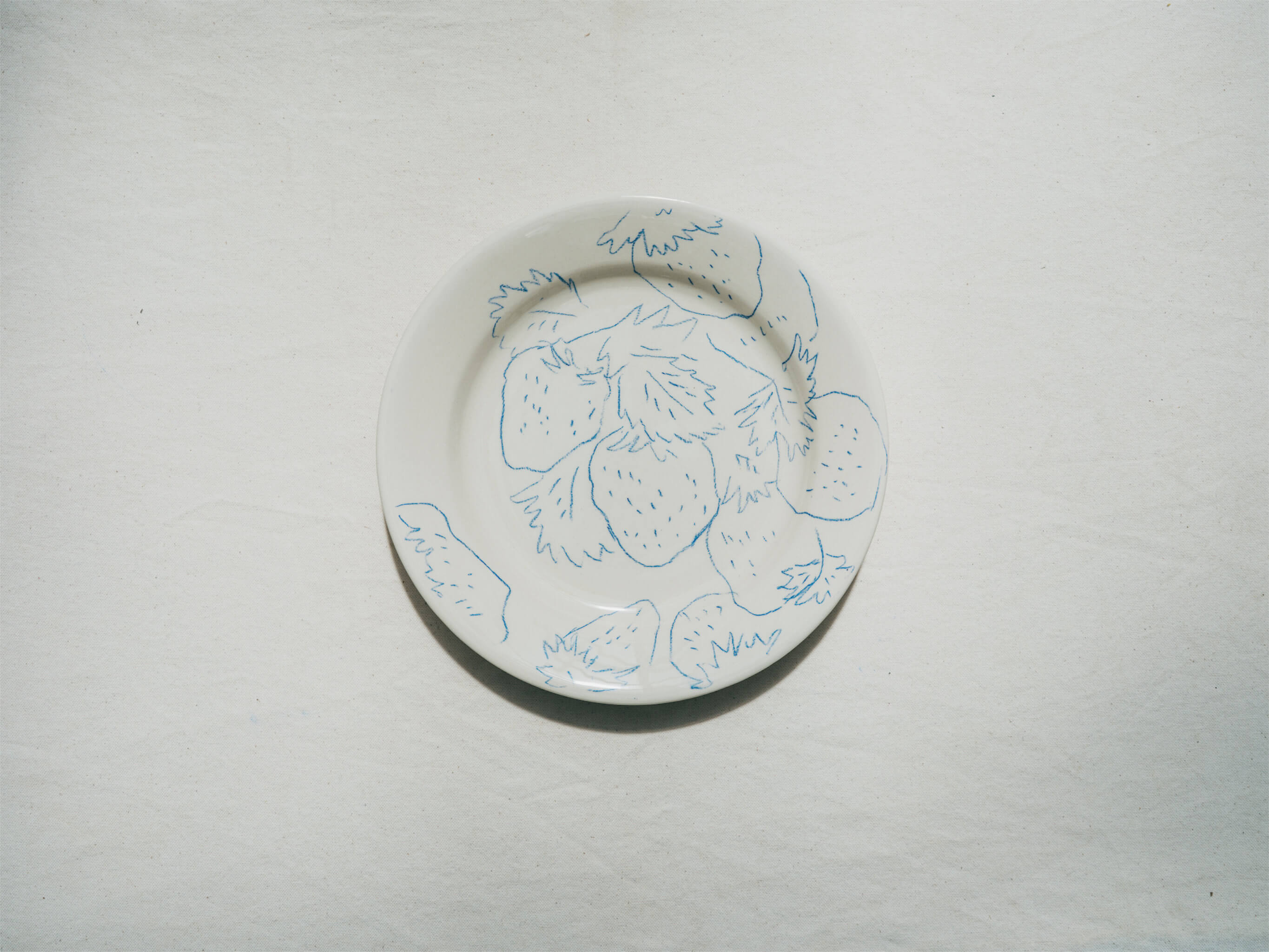 Assiette en faience décorée au crayon à oxydes puis émaillée par l'atelier grand soleil, à Paris. Personnalisable avec une phrase. Motif : fraises