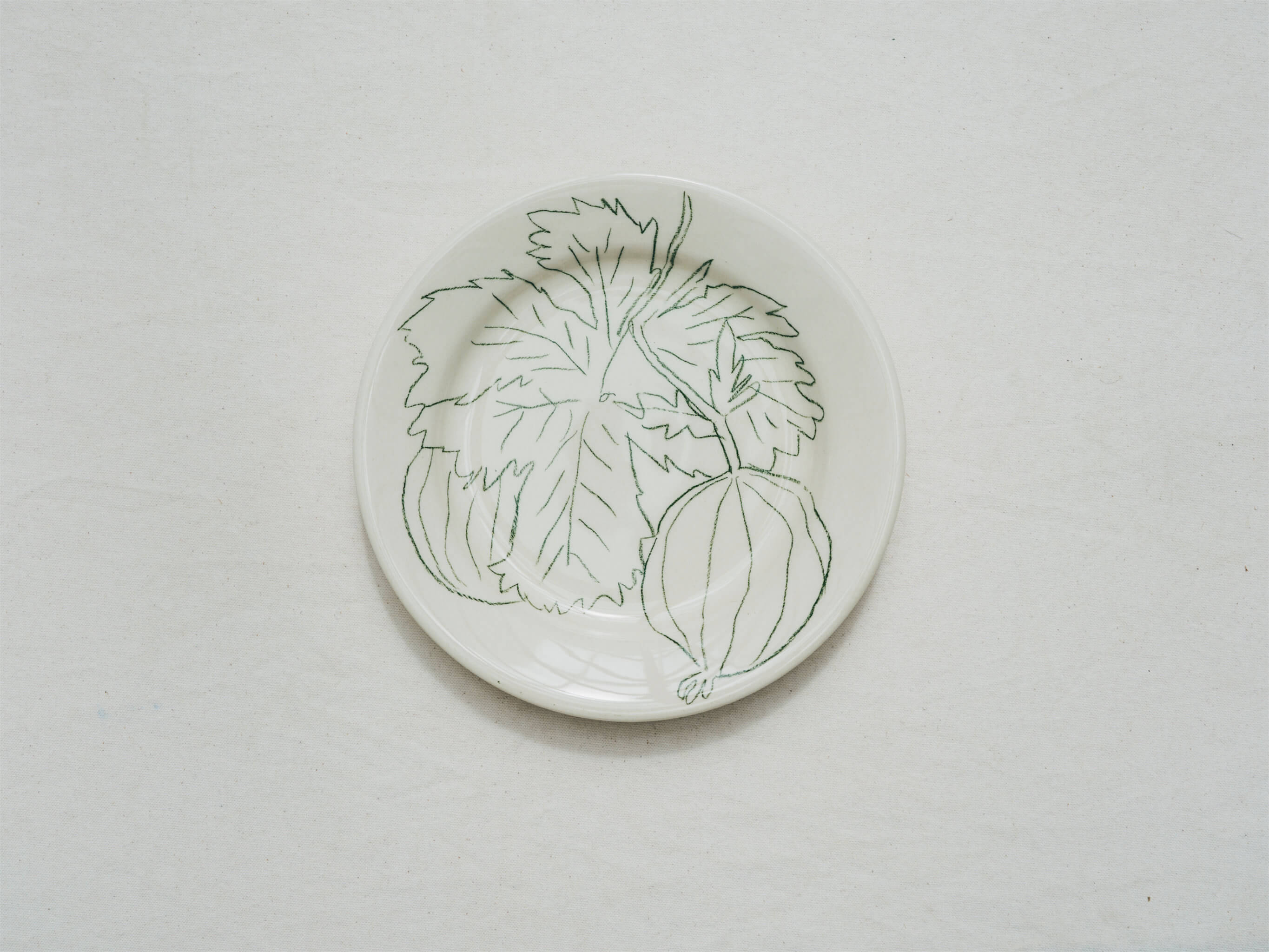 Assiette en faience décorée au crayon à oxydes puis émaillée par l'atelier grand soleil, à Paris. Personnalisable avec une phrase. Motif : courgette ronde