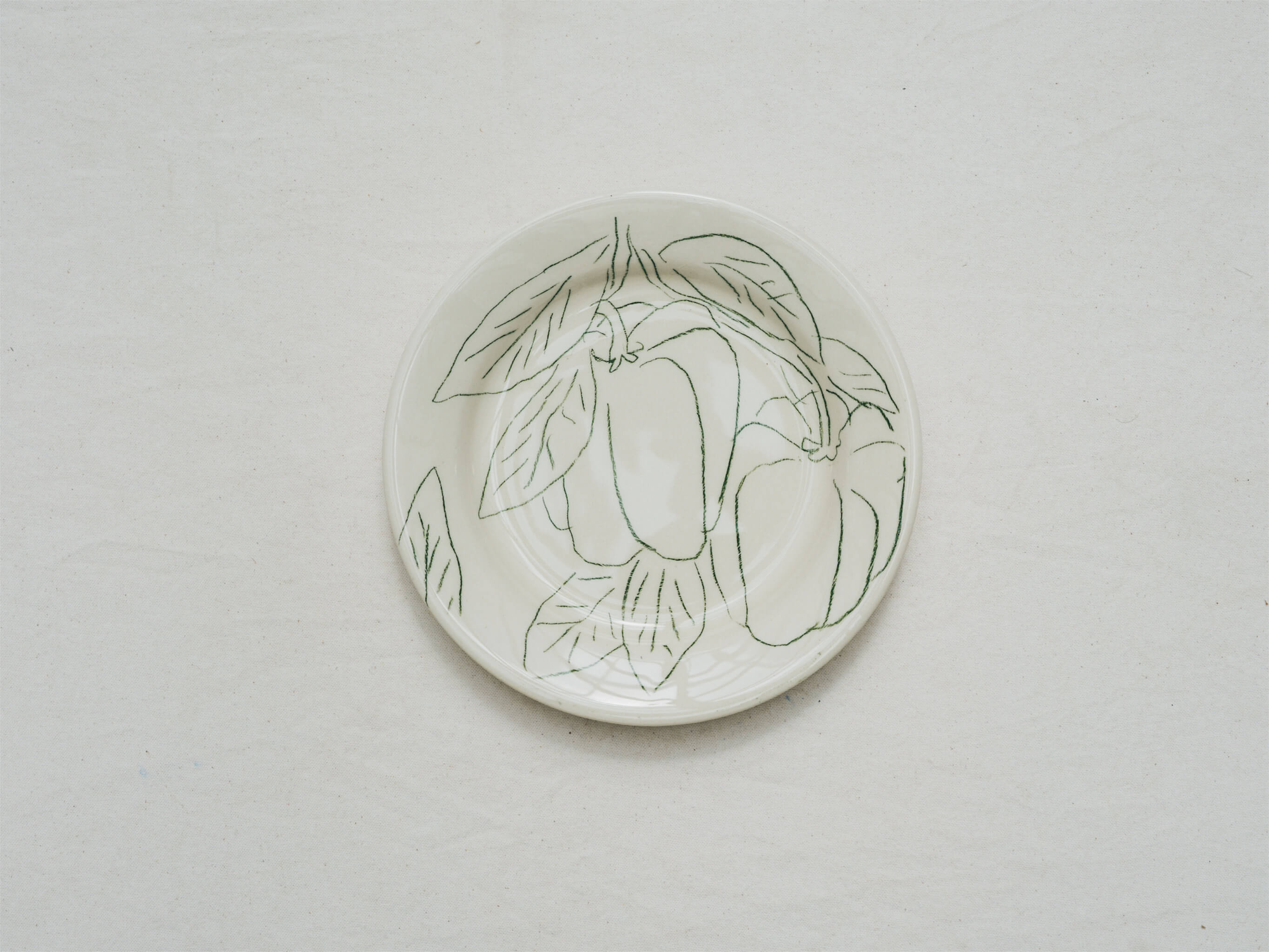Assiette en faience décorée au crayon à oxydes puis émaillée par l'atelier grand soleil, à Paris. Personnalisable avec une phrase. Motif : poivrons