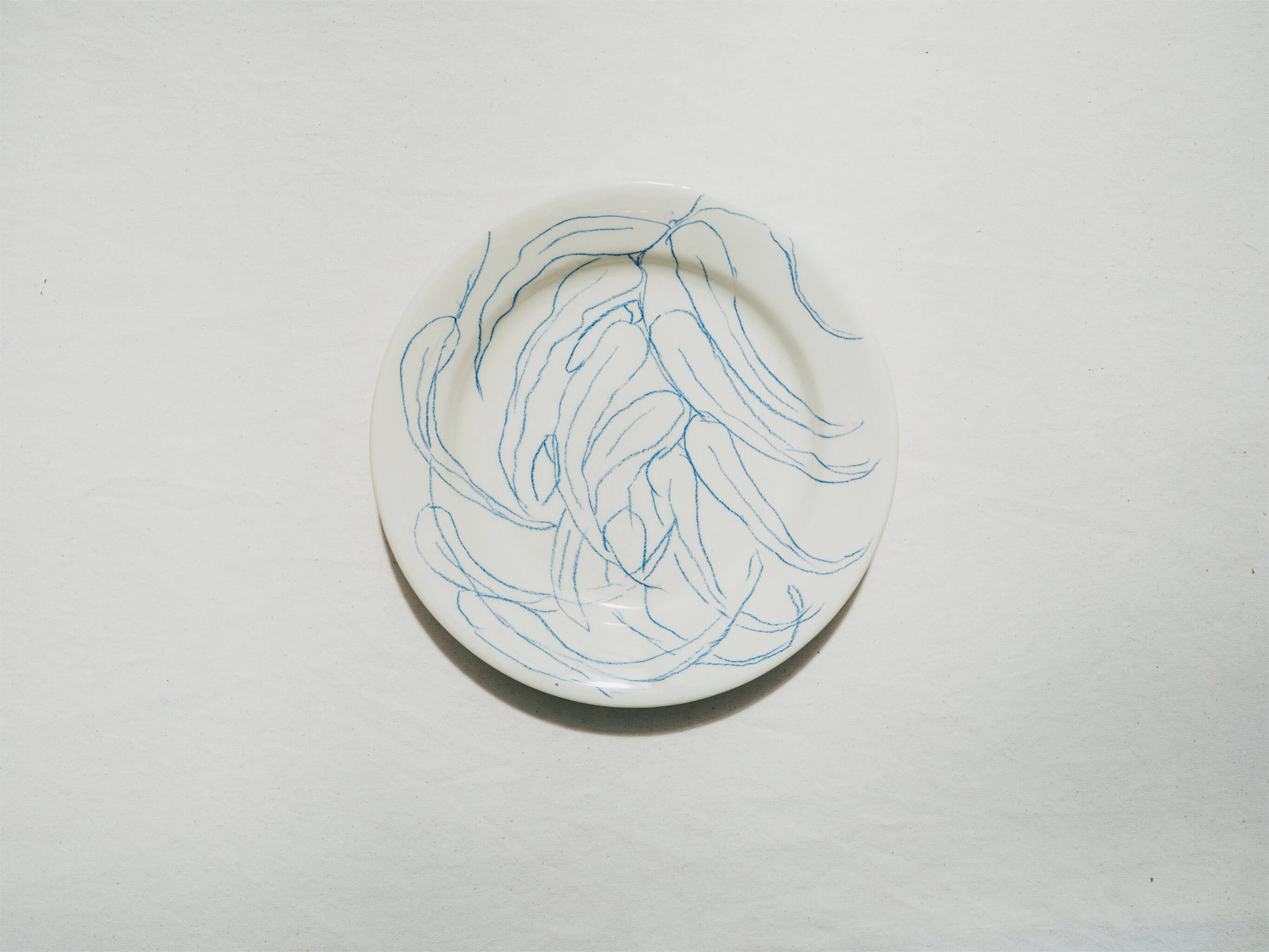 Assiette en faience décorée au crayon à oxydes puis émaillée par l'atelier grand soleil, à Paris. Personnalisable avec une phrase. Motif : longues feuilles