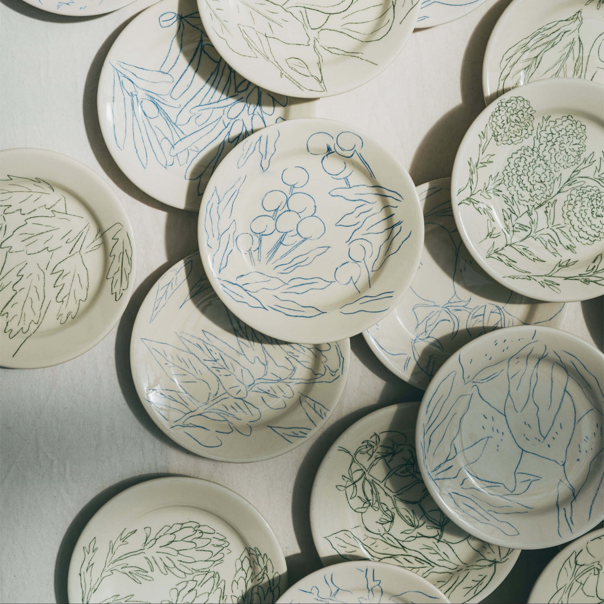 Ensemble d'assiettes en faience décorées au crayon à oxydes puis émaillées par l'atelier grand soleil, à Paris. Personnalisables avec une phrase.