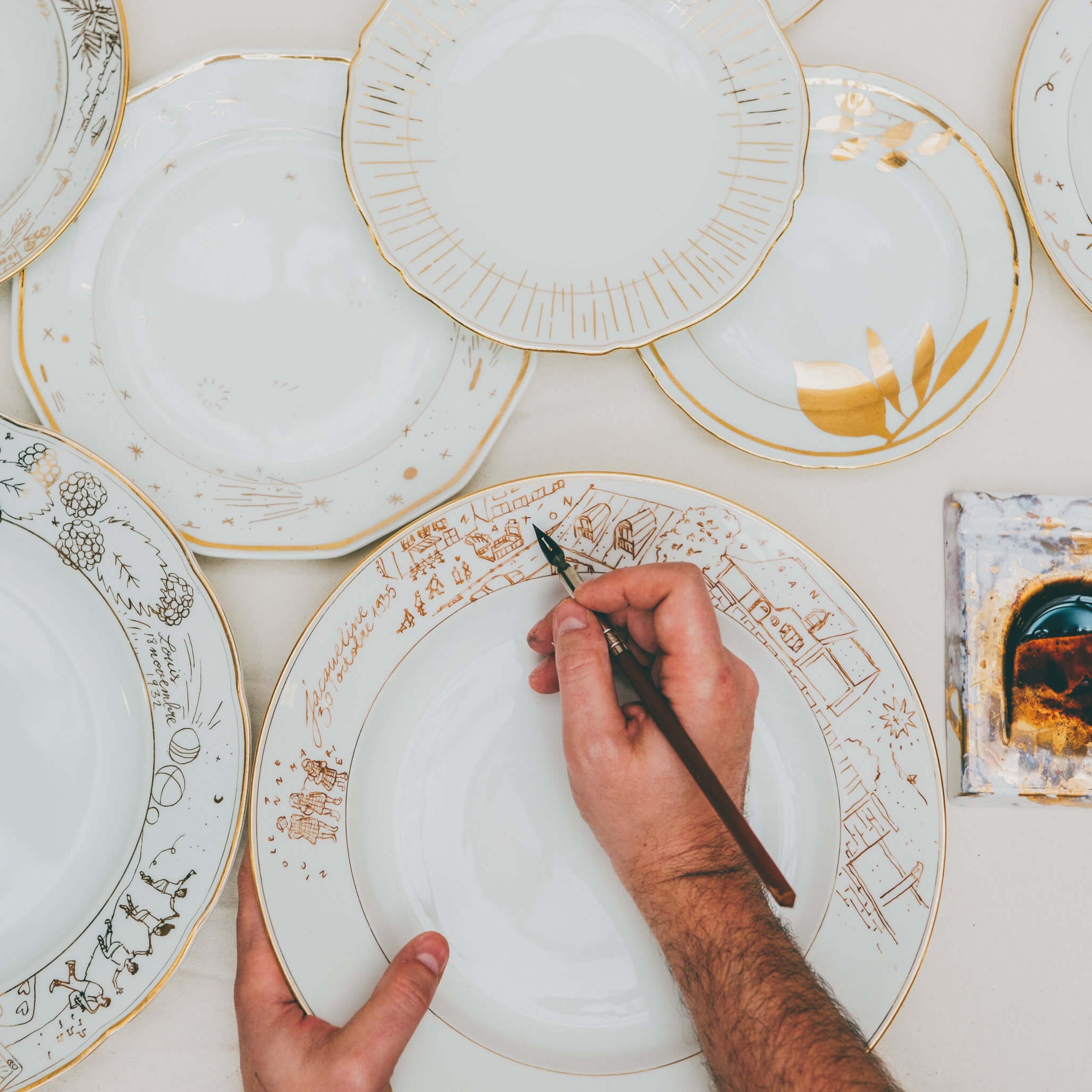 Cette photo représente un ensemble d'assiettes qui ont été décorées à l'or et à la plume lors d'un atelier de 3h à l'Atelier Grand Soleil à Paris
