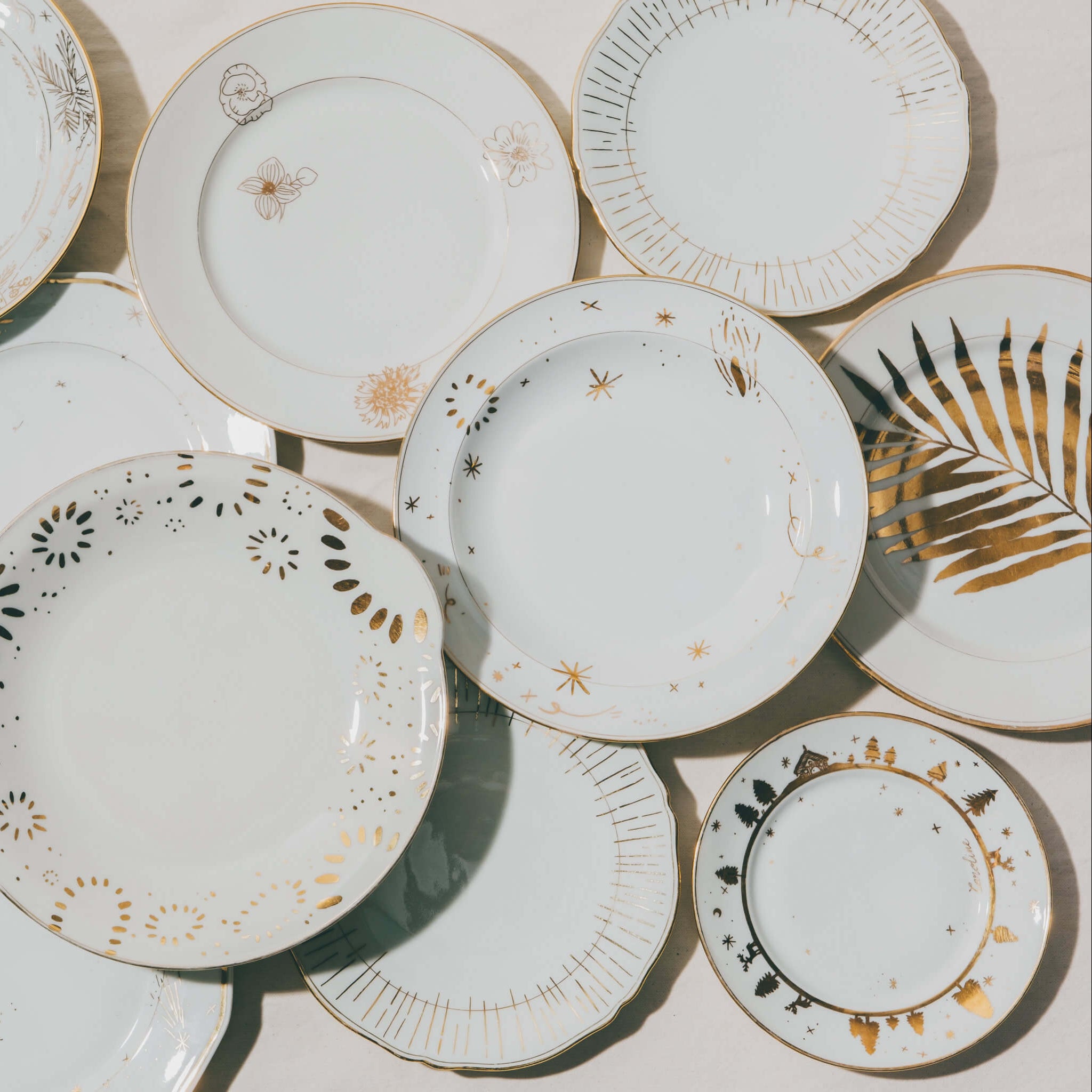 Cette photo représente un ensemble d'assiettes qui ont été décorées à l'or et à la plume lors d'un atelier de 3h à l'Atelier Grand Soleil à Paris