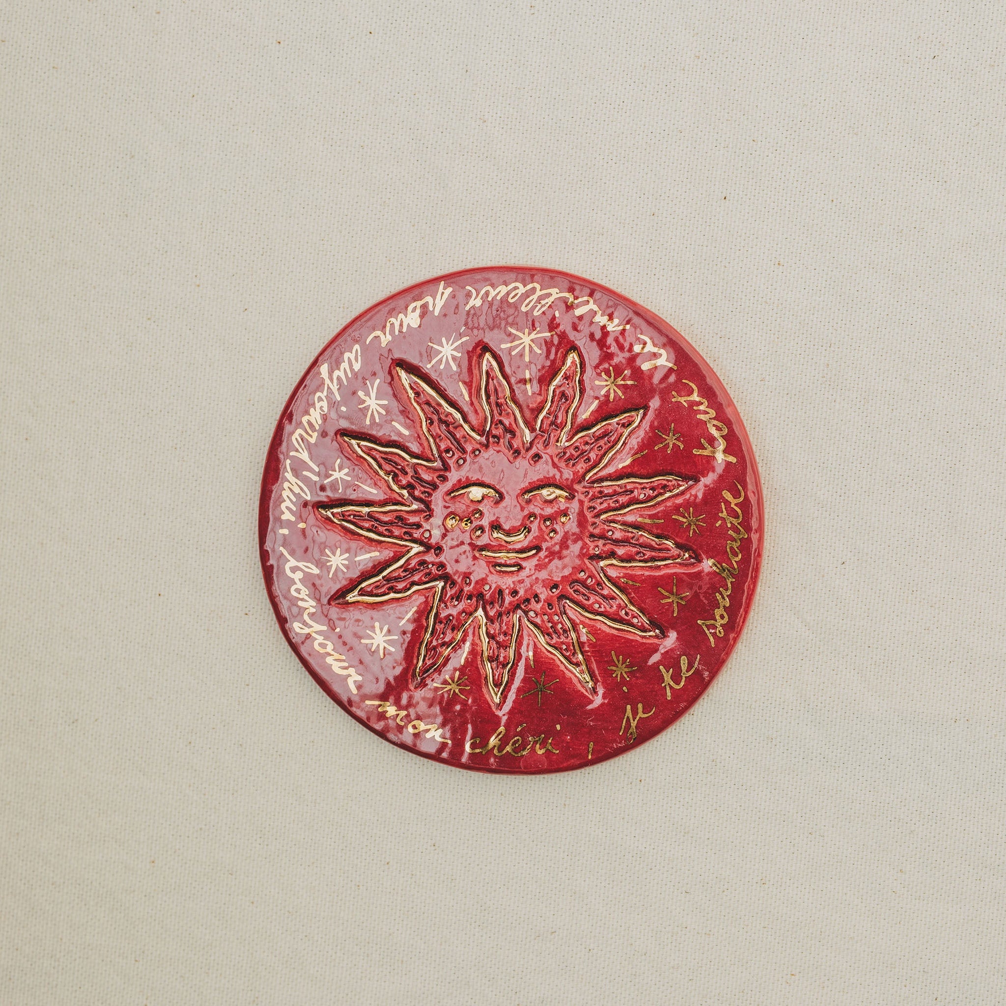 Médaille petit soleil en faïence personnalisée à la main, à l'or et à la plume. Atelier grand soleil. Couleur : rouge