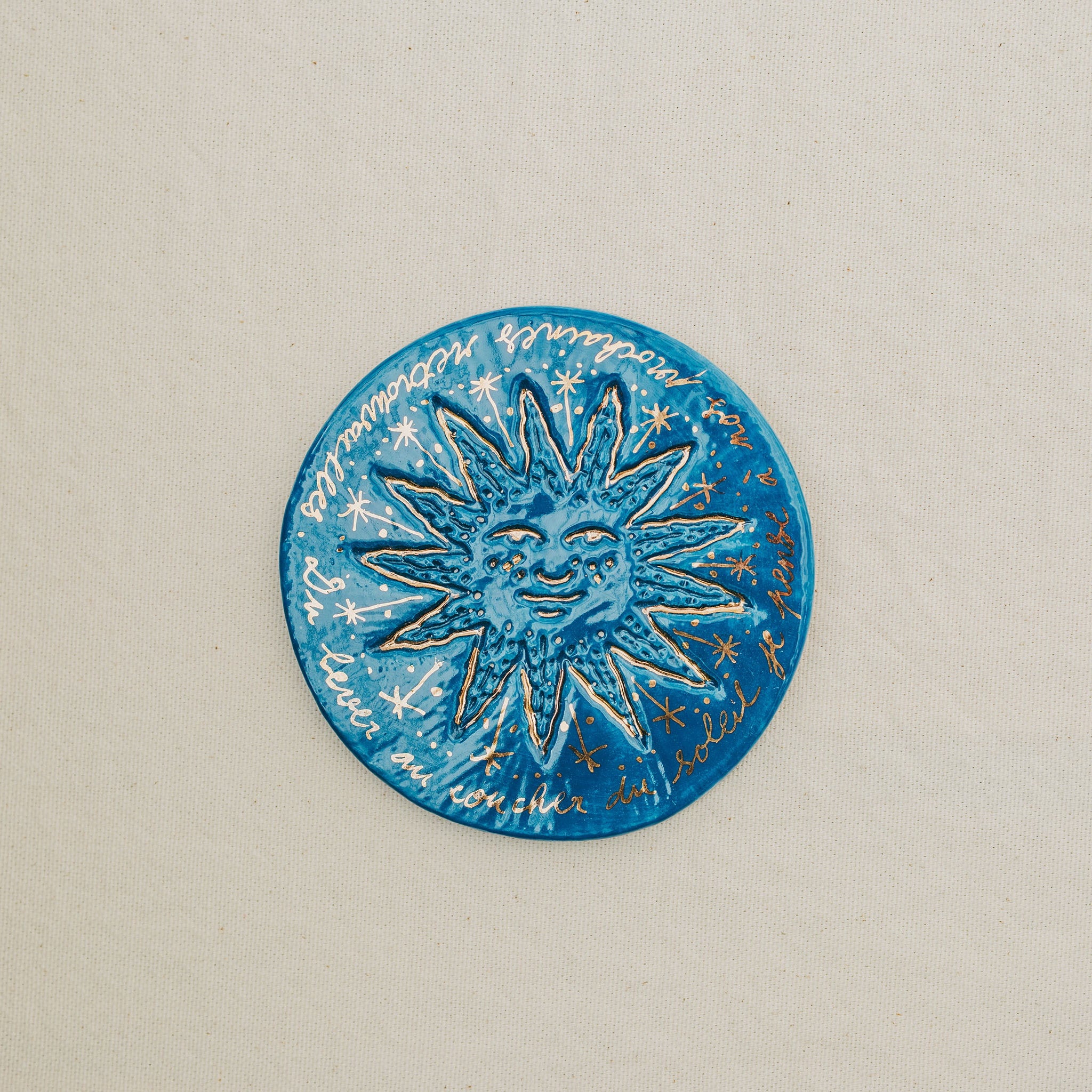 Médaille petit soleil en faïence personnalisée à la main, à l'or et à la plume. Atelier grand soleil. Couleur : bleu foncé
