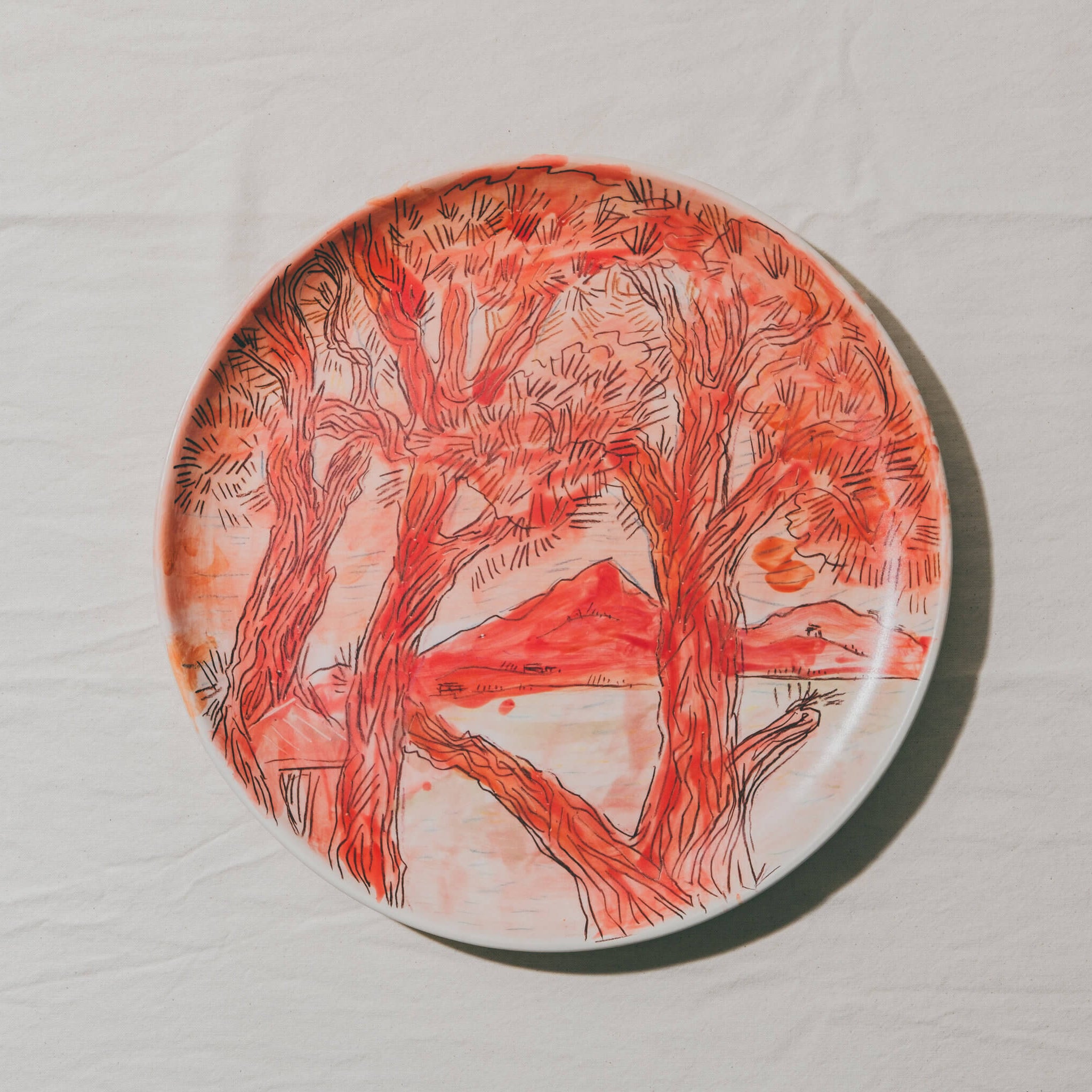 Plat moulé à l’Atelier Grand Soleil, en faïence décorée au crayon à oxyde, à l’engobe puis émaillée transparent.
Les plats sont compatibles avec un lavage en machine en mode éco.
Possibilité de personnalisation à l'or et à la plume. 
Motif : paysage d'arbres, dans les tons rouges