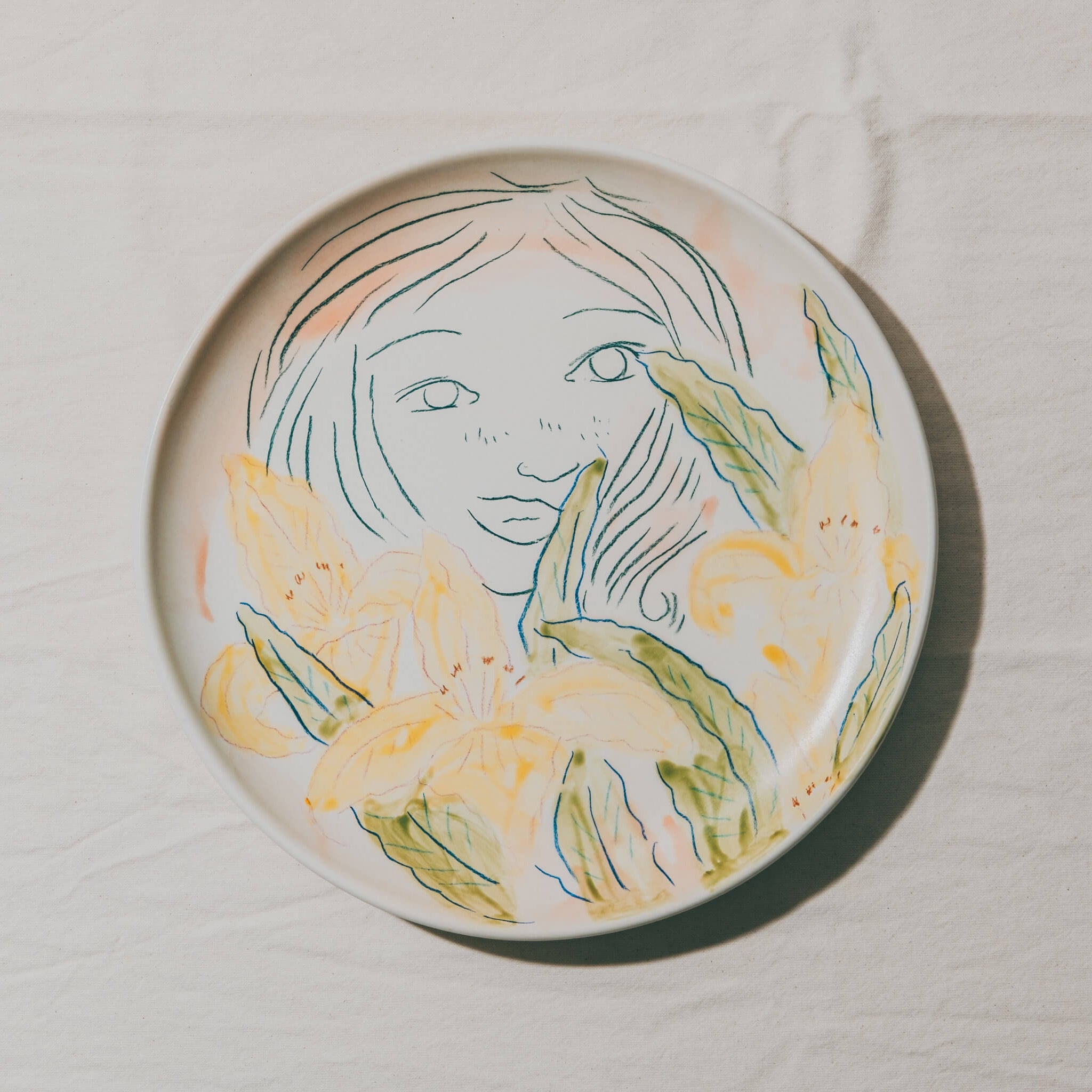 Plat moulé à l’Atelier Grand Soleil, en faïence décorée au crayon à oxyde, à l’engobe puis émaillée transparent.
Les plats sont compatibles avec un lavage en machine en mode éco.
Possibilité de personnalisation à l'or et à la plume. 
Motif : visage de femme et iris