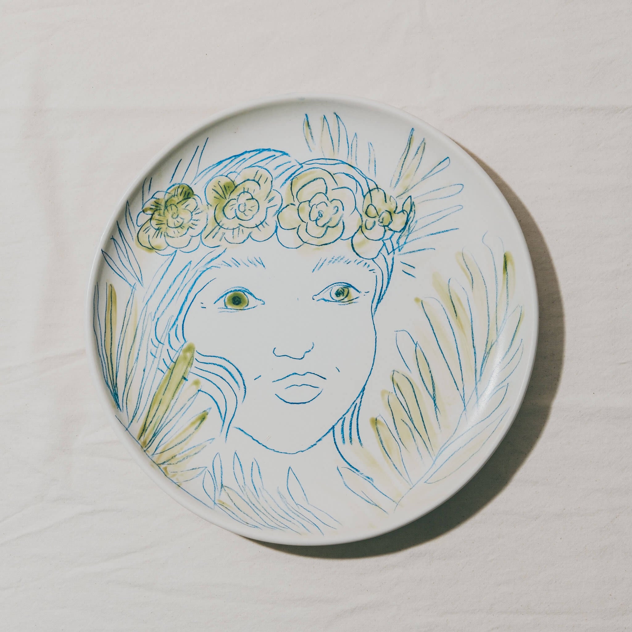 Plat moulé à l’Atelier Grand Soleil, en faïence décorée au crayon à oxyde, à l’engobe puis émaillée transparent.
Les plats sont compatibles avec un lavage en machine en mode éco.
Possibilité de personnalisation à l'or et à la plume. 
Motif : visage de femme et feuilles